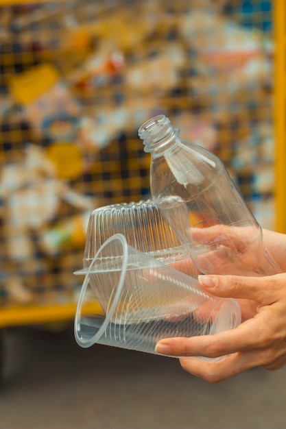 Una botella de plástico, un vaso y una lata en el fondo de un contenedor de basura.