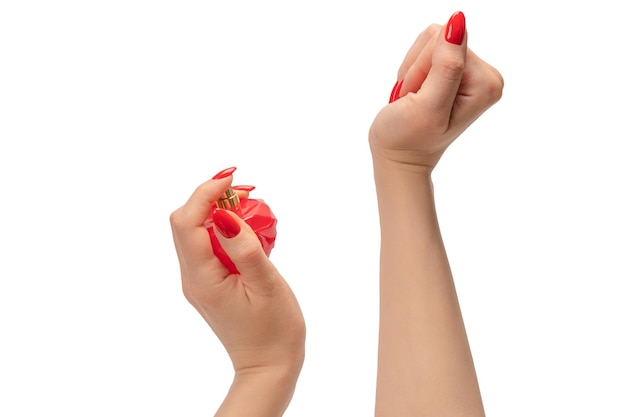 Botella roja de perfume en la mano de la mujer con uñas rojas aisladas sobre un fondo blanco