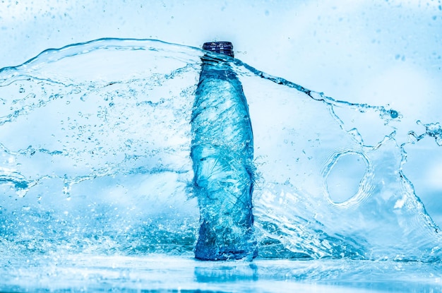 Botella de salpicaduras de agua sobre un fondo azul.