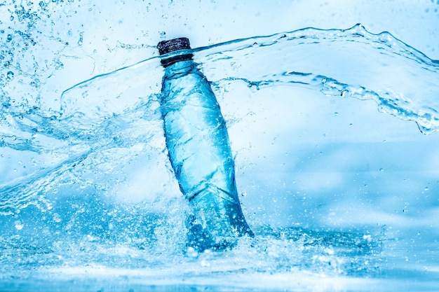 Botella de salpicaduras de agua sobre un fondo azul.