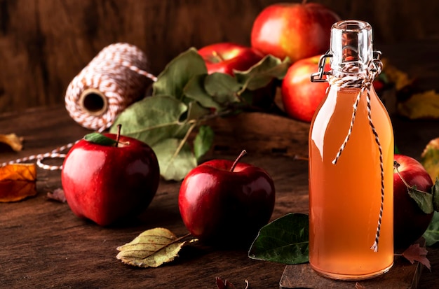 Botella de sidra de manzana con palitos de canela, clavo y anís sobre fondo de madera Bebida tradicional de otoño invierno y cóctel