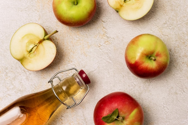 Botella de sidra de manzana sobre fondo de hormigón Manzanas crudas Vinagre de manzana o jugo de manzana Vista superior