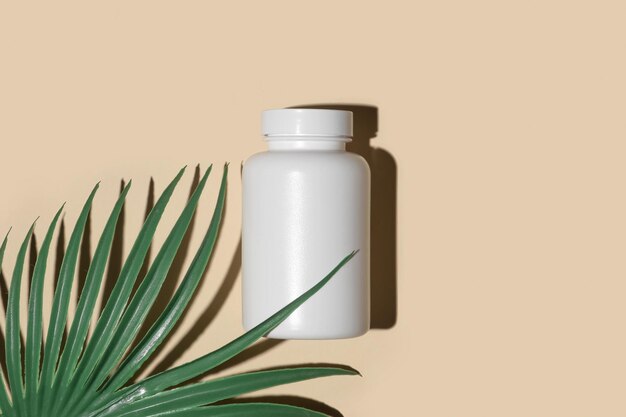 Botella de suplemento blanco Maqueta de medicina Etiqueta en blanco Plantilla de vitamina Bio orgánica natural Frasco de pastillas Fondo de color de estudio beige Embalaje transparente Vista superior Presentación del producto de moda Hoja verde