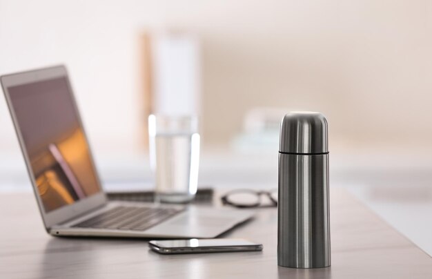 Botella térmica en la mesa en una oficina moderna
