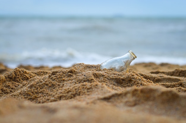 La botella vacía está enterrada en la arena.