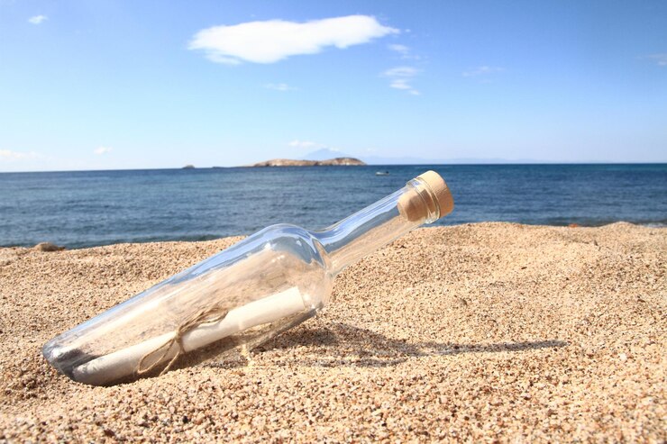 Foto botella varada en la playa con un mensaje dentro