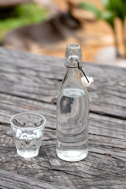 Botella y vaso con agua sobre la mesa de madera