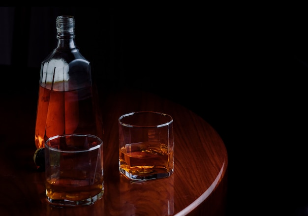 Una botella y vasos de licor en mesa de madera