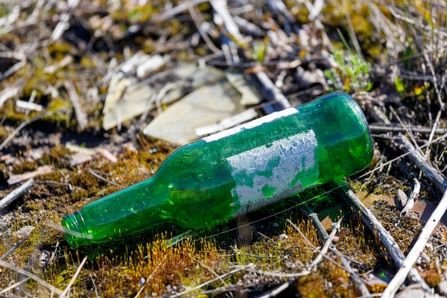 Botella verde tirado en el suelo en la naturaleza. Foto de alta calidad
