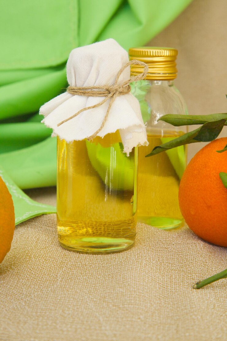 Foto una botella de vidrio de aceite de mandarina. frutas frescas de mandarina en el fondo.
