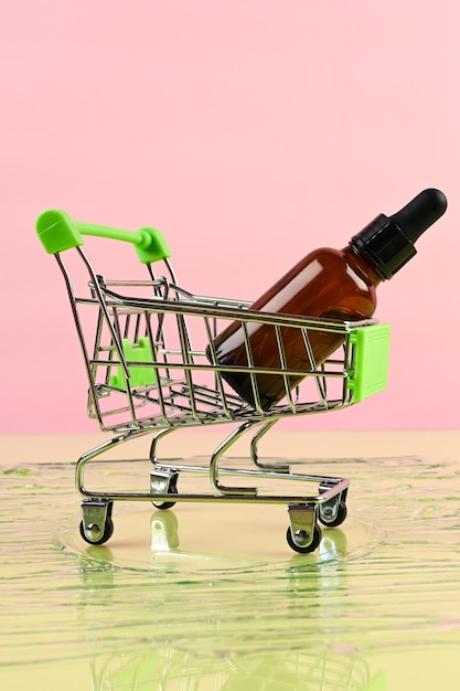 Botella de vidrio en carrito de compras sobre fondo pastel Maqueta de productos de belleza para el cuidado de la piel Tienda de cosméticos en línea