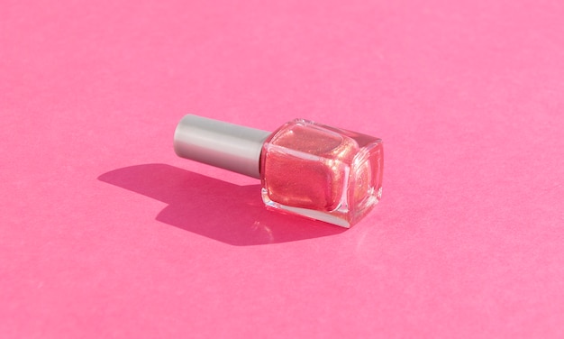 botella de vidrio de esmalte de uñas en rosa