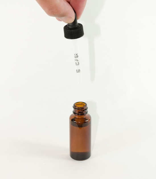 Foto botella de vidrio con gotero sostenida con una mano