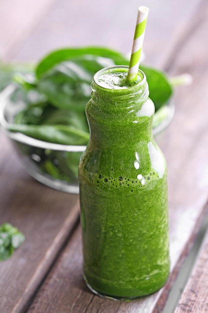 Botella de vidrio de jugo de espinacas en primer plano de la mesa de madera