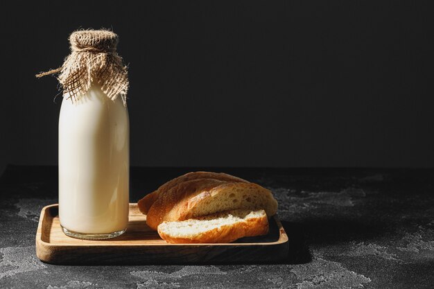 Botella de vidrio de leche con pan baguette en rodajas