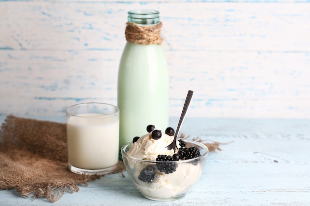 Botella de vidrio de leche y requesón sobre superficie de madera