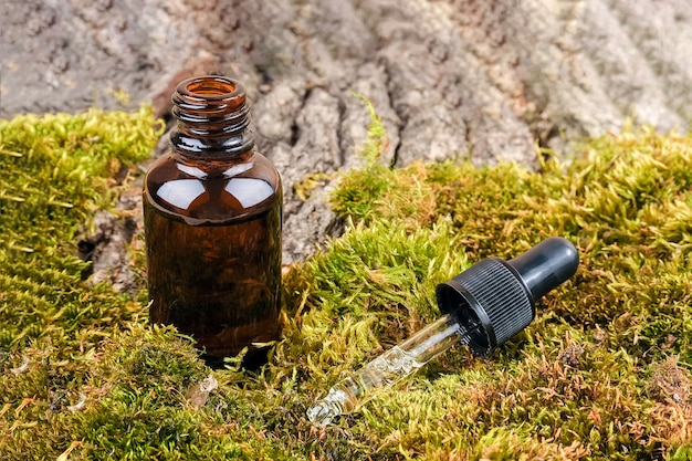 Una botella de vidrio marrón y una pipeta y corteza de árbol.