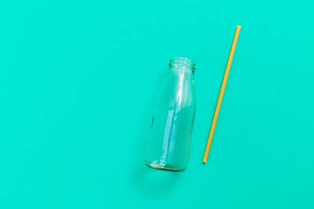 Botella de vidrio con paja de pasta ecológica en imagen de fondo verde con vista superior del espacio de copia