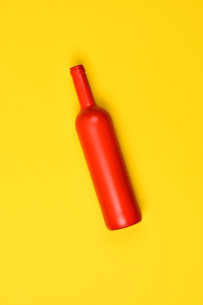 Botella de vidrio rojo sobre fondo amarillo