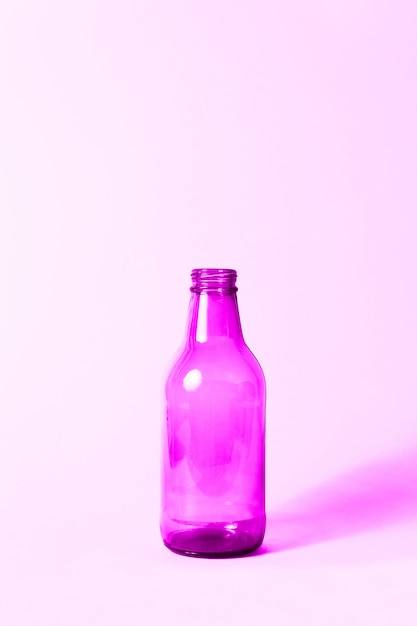 Foto botella de vidrio rosa neón sobre rosa