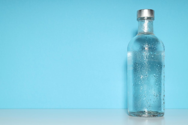 Foto botella de vidrio sobre fondo azul espacio para texto