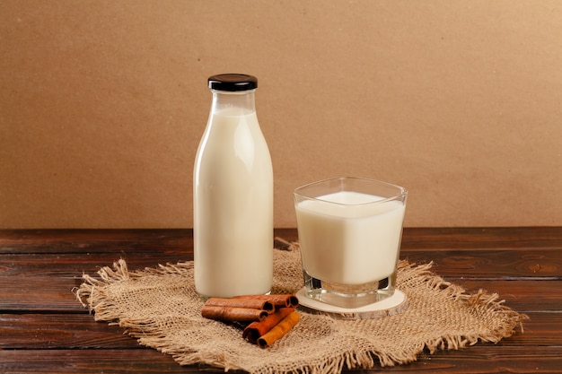 Botella de vidrio y vaso de vidrio con vista frontal de la leche