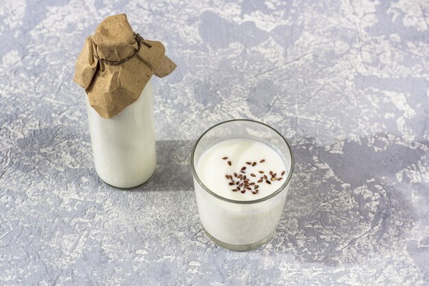 Botella de vidrio y vaso de yogurt con semillas de lino.