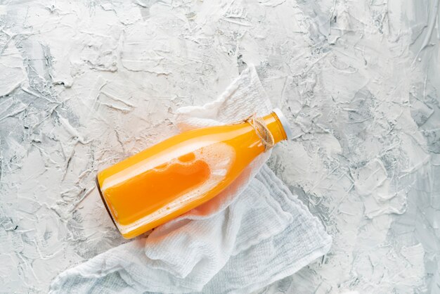 Botella de vidrio con un zumo de naranja exprimido, cortado en rodajas de media naranja.