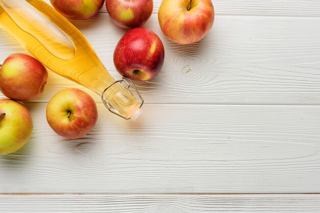 Foto una botella de vinagre de sidra de manzana o jugo con manzanas sobre un fondo blanco con espacio de copia. composición laicos plana con sidra de manzana en un primer plano de una botella de vidrio.