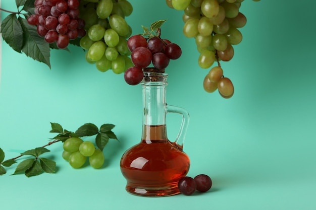 Botella de vinagre y uva sobre fondo de menta