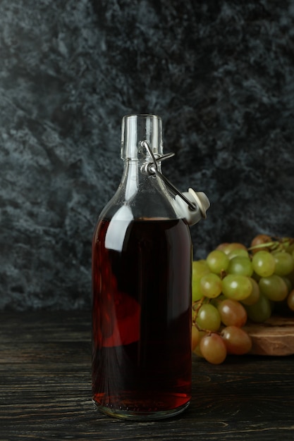 Botella de vinagre y uva sobre mesa de madera rústica