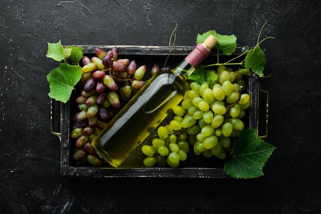 Botella de vino blanco y uvas frescas en una mesa de piedra negra Vista superior Espacio libre para su texto