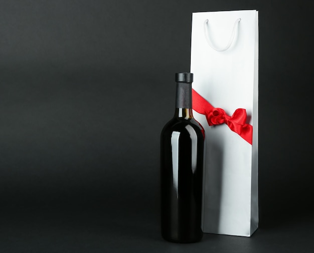 Foto botella de vino y bolsa de regalo sobre fondo oscuro