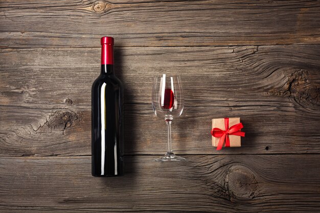 Foto botella de vino con la caja de la copa de vino y de regalo en fondo de madera. vista superior con espacio de copia para su texto.