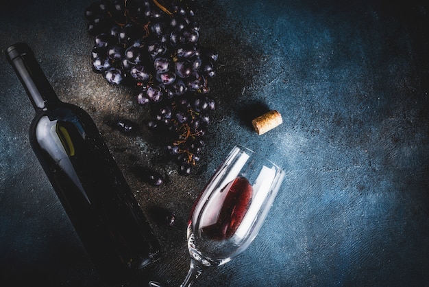 Botella de vino con copa y uvas.