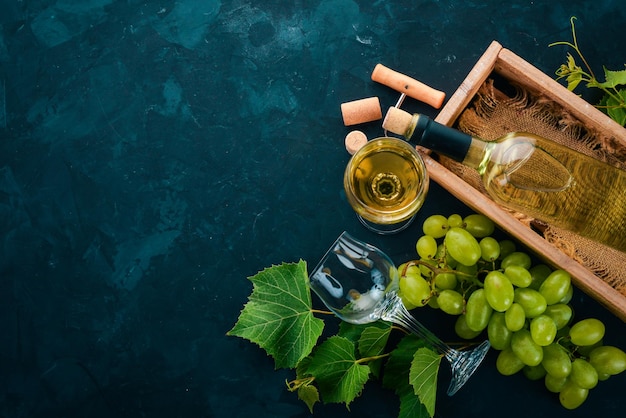 Una botella de vino con copas y uvas Hojas de uva Vista superior Sobre un fondo de piedra negra Espacio libre para texto