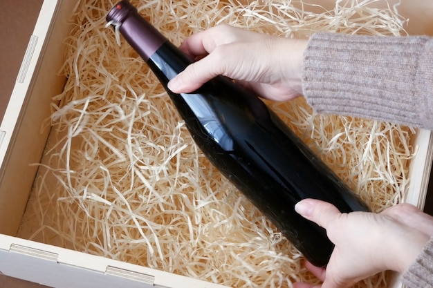 Botella de vino de élite caro en una caja de madera con virutas