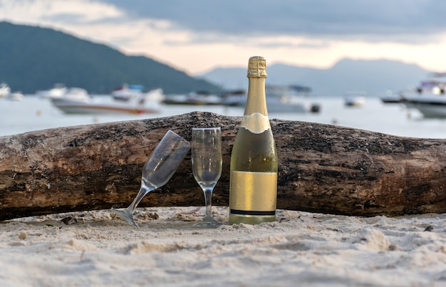 Botella de vino espumoso con copas de champán en la playa