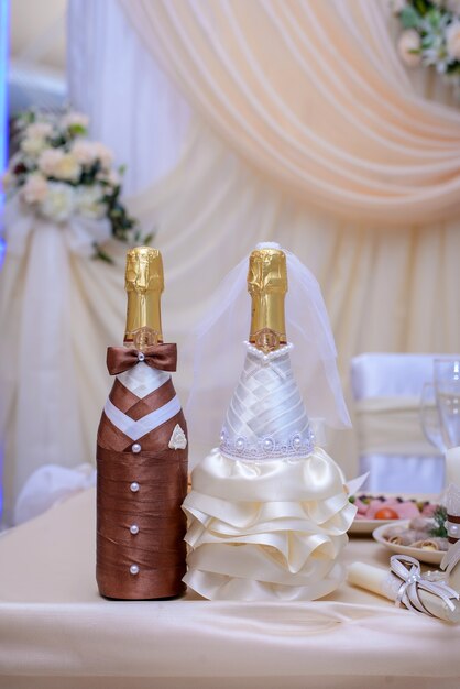 Botella de vino espumoso en una hermosa decoración de boda con los trajes de los novios en tonos beige