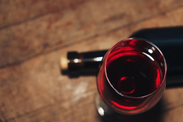 Botella de vino rojo y vaso de vino en una vieja mesa de madera