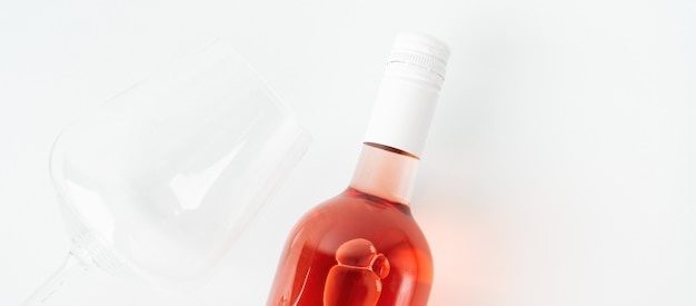 Botella de vino rosado con copa de vino.