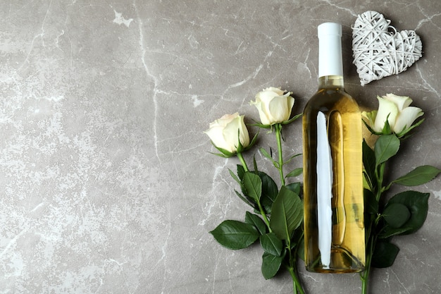 Botella de vino, rosas y corazón en gris con textura