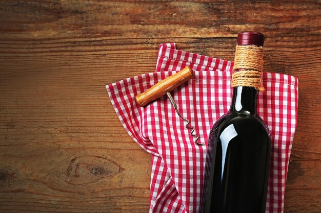 Botella de vino con un sacacorchos sobre fondo de madera