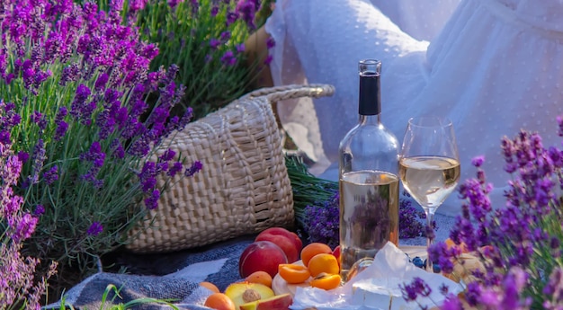 Una botella de vino sobre un fondo de un campo de lavanda Copas con frutas de vino