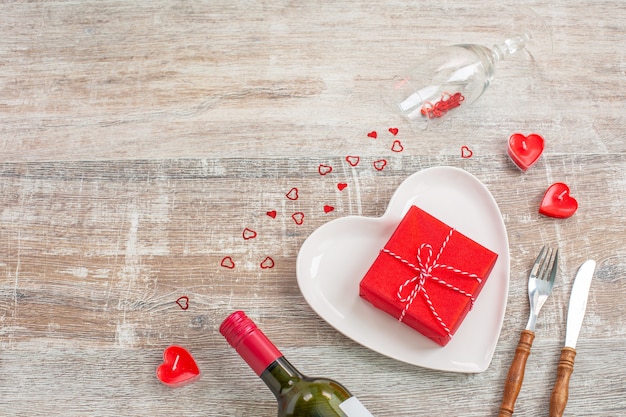 Botella de vino tinto y caja de regalo de amor, velas, flores.