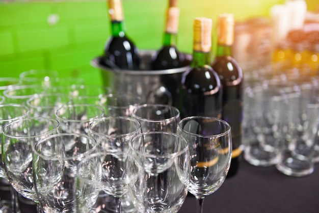 Botella de vino tinto en un cubo de hielo y copa de vino en el fondo de la mesa / copa de champán para la fiesta de celebración