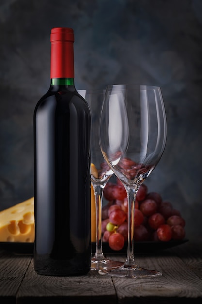 Botella de vino tinto y dos vasos vacíos closeup sobre una mesa de madera