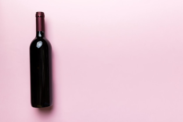 Foto una botella de vino tinto en la mesa de colores. vista plana endecha, superior con espacio de copia.