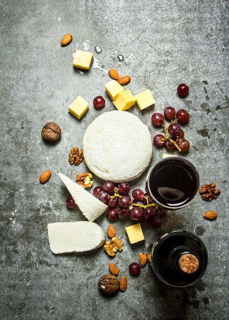 Botella de vino tinto con nueces y queso. Sobre la mesa de piedra.