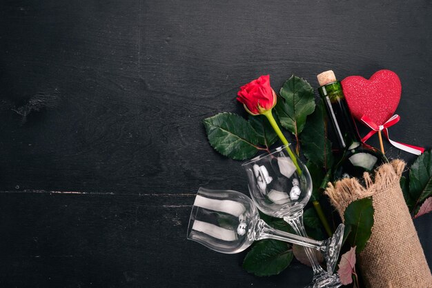 Una botella de vino tinto y un ramo de rosas rojas. Día de San Valentín. Sobre un fondo de madera. Vista superior. Espacio libre para su texto.